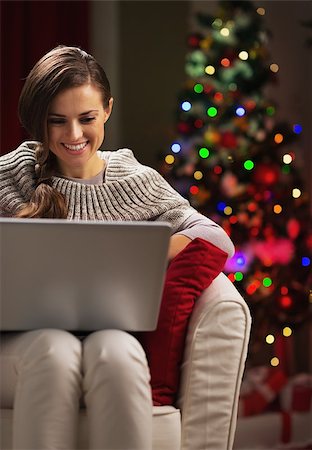simsearch:400-06419734,k - Smiling young woman near christmas tree using laptop Stock Photo - Budget Royalty-Free & Subscription, Code: 400-06929625
