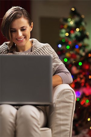 simsearch:400-06419734,k - Smiling young woman near christmas tree using laptop Stock Photo - Budget Royalty-Free & Subscription, Code: 400-06929638