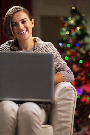 Happy young woman near christmas tree with laptop Stock Photo - Budget Royalty-Free & Subscription, Code: 400-06929639