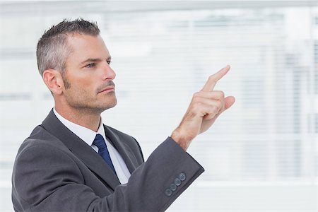 simsearch:400-07275251,k - Pensive businessman in bright office pointing out while looking away Stock Photo - Budget Royalty-Free & Subscription, Code: 400-06929764