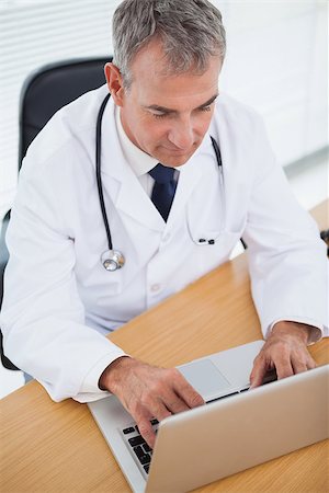 simsearch:695-05771285,k - Experienced doctor typing on his laptop in bright office Foto de stock - Royalty-Free Super Valor e Assinatura, Número: 400-06929946