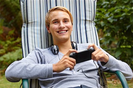 Young male relaxing in lounge outdoors with a game console and headphones. Stock Photo - Budget Royalty-Free & Subscription, Code: 400-06922009