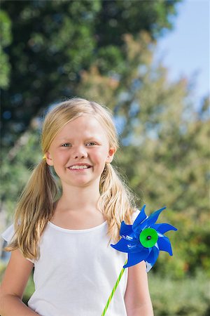 Cute blonde girl holding pinwheel smiling at camera in the park in sunshine Foto de stock - Super Valor sin royalties y Suscripción, Código: 400-06934037