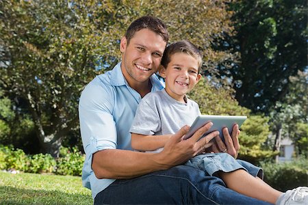 family with tablet in the park - Happy dad and son smiling in a park with a tablet pc Photographie de stock - Aubaine LD & Abonnement, Code: 400-06934076