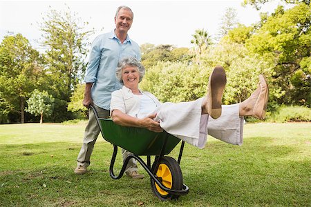 Cheerful man pushing his wife in a wheelbarrow and smiling at camera Stock Photo - Budget Royalty-Free & Subscription, Code: 400-06934209