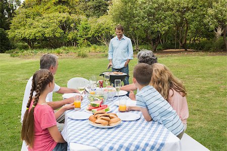 Cheerful extended family sitting at picnic table watching father at the barbecue Stock Photo - Budget Royalty-Free & Subscription, Code: 400-06934298