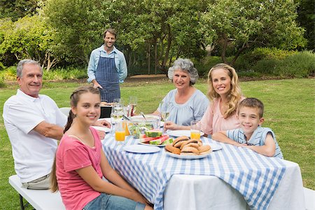 Happy extended family having a barbecue being cooked by father looking at camera Stock Photo - Budget Royalty-Free & Subscription, Code: 400-06934304