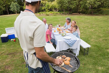 Father in chefs hat and apron cooking barbecue for his family sitting at picnic table Foto de stock - Super Valor sin royalties y Suscripción, Código: 400-06934307