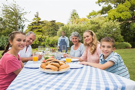Smiling extended family waiting for barbecue being cooked by father smiling at camera Stock Photo - Budget Royalty-Free & Subscription, Code: 400-06934302