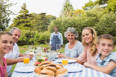 Happy extended family waiting for barbecue being cooked by father smiling at camera Foto de stock - Super Valor sin royalties y Suscripción, Código: 400-06934303