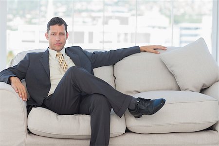 simsearch:400-06879262,k - Serious businessman in suit posing sitting on sofa in bright office Stock Photo - Budget Royalty-Free & Subscription, Code: 400-06934616