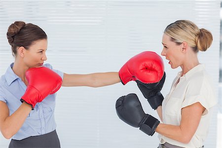 Brown haired businesswoman punching her blond colleague during boxing match in bright office Stock Photo - Budget Royalty-Free & Subscription, Code: 400-06934611