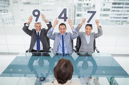 employee hold a sign - Smiling interview panel in bright office holding signs above their head giving marks to their applicant Stock Photo - Budget Royalty-Free & Subscription, Code: 400-06934705