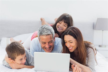simsearch:400-06930138,k - Family lying on bed using their laptop at home Stock Photo - Budget Royalty-Free & Subscription, Code: 400-06930084