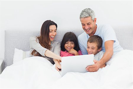 simsearch:400-06930138,k - Family lying in bed using their laptop at home Stock Photo - Budget Royalty-Free & Subscription, Code: 400-06930089
