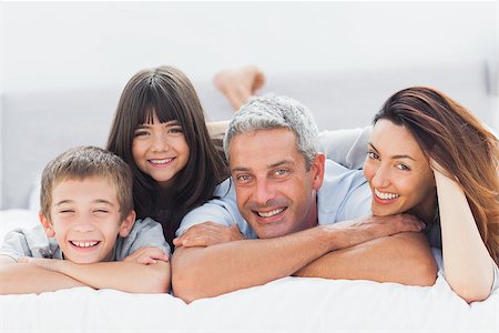 simsearch:400-06930138,k - Cute family lying on bed and smiling at camera at home Stock Photo - Budget Royalty-Free & Subscription, Code: 400-06930082