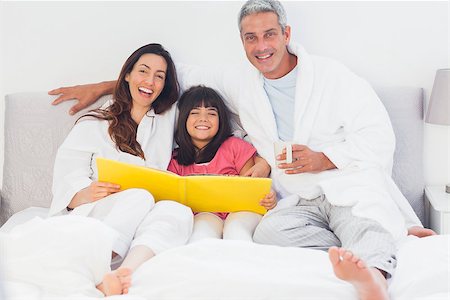 simsearch:400-06930138,k - Parents with their daughter on bed looking together at photograph album at home Stock Photo - Budget Royalty-Free & Subscription, Code: 400-06930096