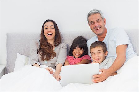 simsearch:400-06930138,k - Happy family lying in bed using their laptop at home Stock Photo - Budget Royalty-Free & Subscription, Code: 400-06930091