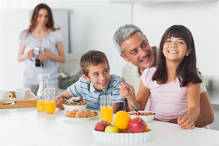 simsearch:400-06930138,k - Smiling family eating breakfast in kitchen together at home Stock Photo - Budget Royalty-Free & Subscription, Code: 400-06930124