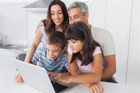 simsearch:400-06930138,k - Family sitting in kitchen using their laptop at home Stock Photo - Budget Royalty-Free & Subscription, Code: 400-06930129