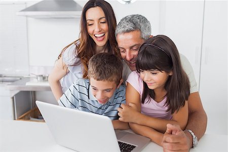 simsearch:400-06930138,k - Smiling family sitting in kitchen using their laptop at home Stock Photo - Budget Royalty-Free & Subscription, Code: 400-06930130