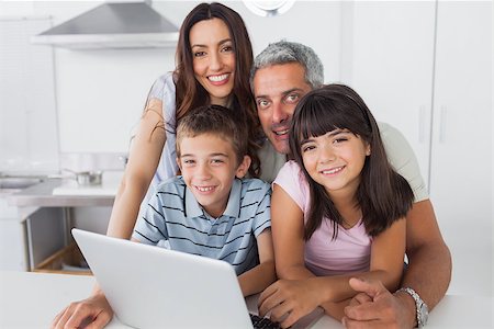 simsearch:400-06930138,k - Happy family sitting in kitchen using their laptop at home Stock Photo - Budget Royalty-Free & Subscription, Code: 400-06930131