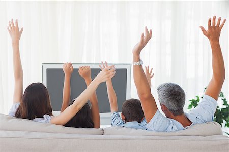 simsearch:400-06930138,k - Family watching televison and rising theirs arms on sofa Stock Photo - Budget Royalty-Free & Subscription, Code: 400-06930163