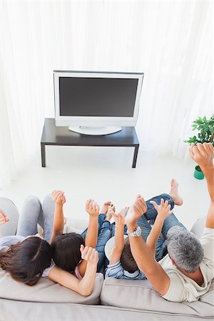 simsearch:400-06930138,k - Family sitting on sofa cheering in front of television at home Stock Photo - Budget Royalty-Free & Subscription, Code: 400-06930171