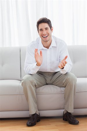 sophisticated home smile - Young man sitting on sofa applauding and smiling at camera Stock Photo - Budget Royalty-Free & Subscription, Code: 400-06930189