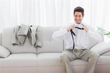 sophisticated home smile - Smiling businessman sitting on sofa loosening his tie at home after long day Stock Photo - Budget Royalty-Free & Subscription, Code: 400-06930201