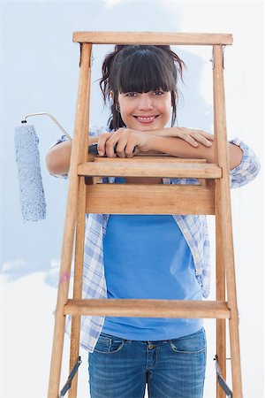 Happy woman holding paint roller leaning on ladder looking at camera Photographie de stock - Aubaine LD & Abonnement, Code: 400-06931064