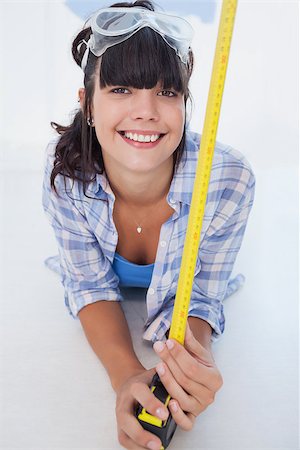 Happy woman lying on floor with measuring tape and safety goggles looking at camera Photographie de stock - Aubaine LD & Abonnement, Code: 400-06931067