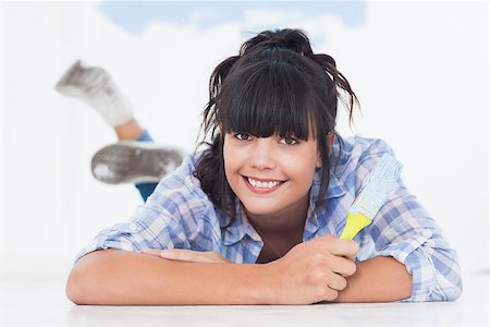 Happy woman lying on floor holding paint brush looking at camera Photographie de stock - Aubaine LD & Abonnement, Code: 400-06931068