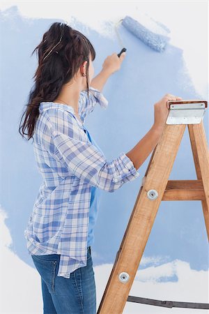 Woman using paint roller to paint wall blue standing on ladder Photographie de stock - Aubaine LD & Abonnement, Code: 400-06931062