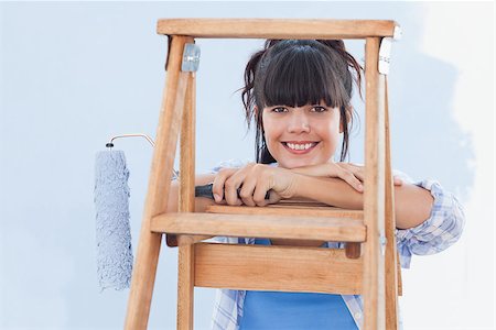 Smiling woman holding paint roller leaning on ladder looking at camera Photographie de stock - Aubaine LD & Abonnement, Code: 400-06931063