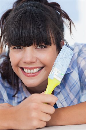 Pretty woman lying on floor holding paint brush smiling at camera Photographie de stock - Aubaine LD & Abonnement, Code: 400-06931070