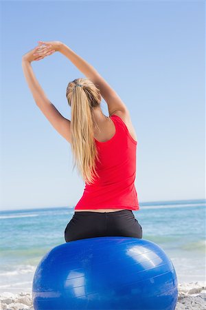 Fit woman sitting on exercise ball looking at sea stretching arms the beach Stock Photo - Budget Royalty-Free & Subscription, Code: 400-06931169