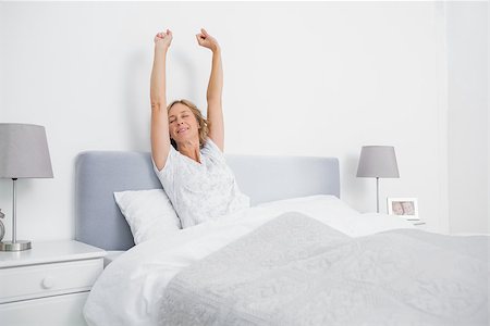 Blonde woman stretching her arms in bed in the morning in bedroom at home Stock Photo - Budget Royalty-Free & Subscription, Code: 400-06931180