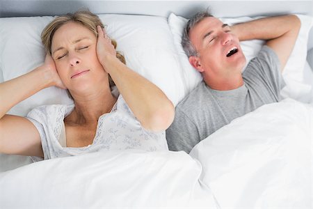 simsearch:400-06891122,k - Wife blocking her ears from noise of husband snoring in bedroom at home Photographie de stock - Aubaine LD & Abonnement, Code: 400-06931236