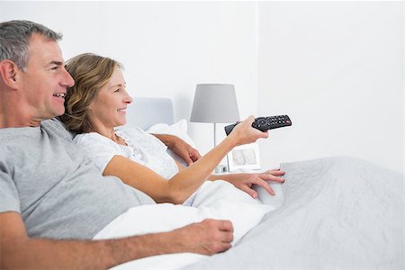 Content couple cuddling in bed watching television at home in bedroom Stock Photo - Budget Royalty-Free & Subscription, Code: 400-06931255