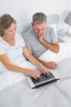 Thoughtful couple using their laptop together in bed at home in bedroom Stock Photo - Budget Royalty-Free & Subscription, Code: 400-06931277