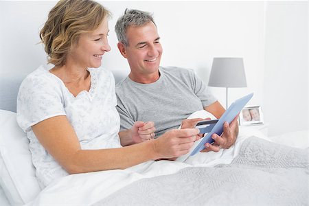 Cheerful couple using their tablet pc to buy online at home in bedroom Stock Photo - Budget Royalty-Free & Subscription, Code: 400-06931282