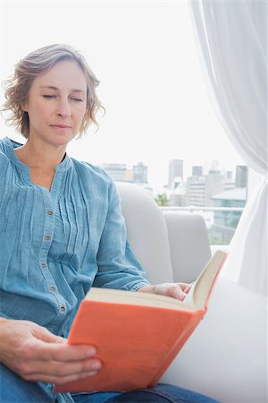 simsearch:400-06872352,k - Content blonde woman sitting on her couch reading a book at home in the sitting room Foto de stock - Royalty-Free Super Valor e Assinatura, Número: 400-06931504