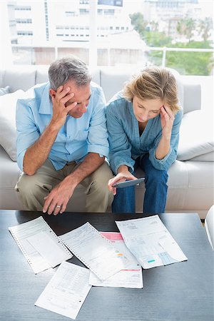 simsearch:400-07333928,k - Worried couple sitting on their couch paying their bills at home in the living room Stock Photo - Budget Royalty-Free & Subscription, Code: 400-06931528