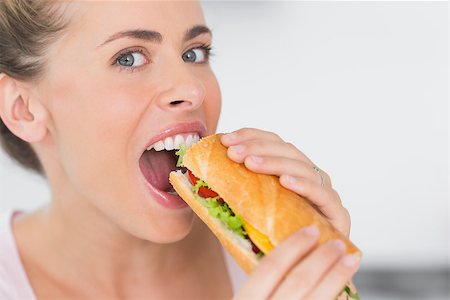 Happy woman eating sandwich and looking at camera at home Stock Photo - Budget Royalty-Free & Subscription, Code: 400-06932571