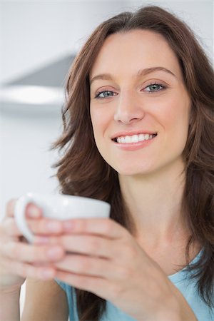simsearch:400-06932687,k - Radiant brunette holding cup of coffee and looking at camera Stock Photo - Budget Royalty-Free & Subscription, Code: 400-06932674