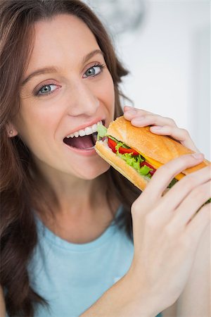 Cute brunette eating sandwich in her kitchen Foto de stock - Super Valor sin royalties y Suscripción, Código: 400-06932683