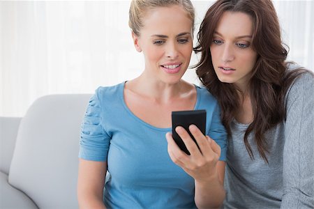 simsearch:400-07059986,k - Friends watching something on their phone and sitting on the sofa Stock Photo - Budget Royalty-Free & Subscription, Code: 400-06932813