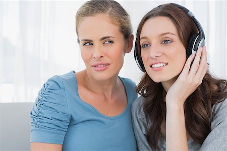 simsearch:400-07059986,k - Brunette wearing headphones with her friend listening sitting on the sofa Stock Photo - Budget Royalty-Free & Subscription, Code: 400-06932830