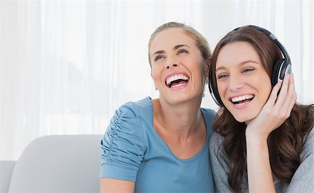 simsearch:400-07059986,k - Cheerful women listening to music sitting on the sofa Stock Photo - Budget Royalty-Free & Subscription, Code: 400-06932832